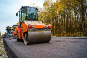 färsk asfalt på motorväg konstruktion webbplats. industriell trottoar maskin läggning. foto