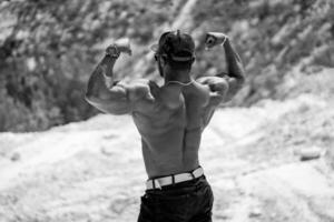 atletisk man med stark tillbaka som visar kraft. stilig kroppsbyggare med naken torso Framställ. foto