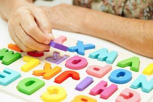 asiatisk äldre kvinna spelar pussel spel för behandling demens förebyggande och alzheimers sjukdom. foto