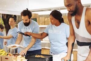 ung volontärer laga mat och hand ut mat till de behövande. Inaktiverad individer och multietnisk människor komma tillsammans till förse skydd och humanitär hjälpa främja enhet och medkänsla i gemenskap. foto