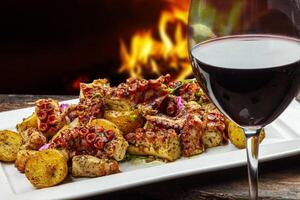 grillad bläckfisk med potatis och glas av röd vin foto