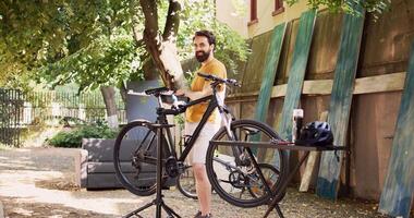 ungdomlig man i Hem gård bärande hans verktygslåda och framställning för cykel sommar underhåll. sidovy porträtt av caucasian manlig innehav annorlunda specialiserade utrustning till reparera cykel. foto