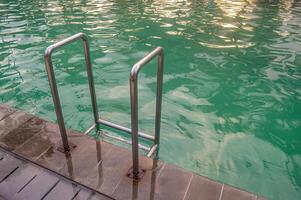 en rostfri stål simning stege i en simning slå samman med turkos vatten foto
