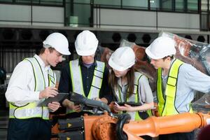 grupp av ingenjörer och tekniker arbetssätt tillsammans i en robot ärm fabrik. inspekterande robot ärm innan leverera till kunder foto