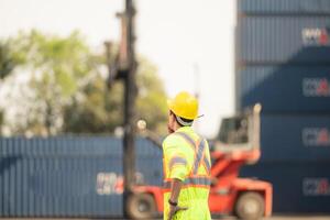 arbetare i de importera och exportera industri använda sig av walkie talkies till kommunicera med drivrutiner av nå stacker behållare i ett tömma behållare lager. foto