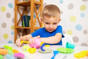 söt barn Sammanträde på de tabell och spelar med playdough foto