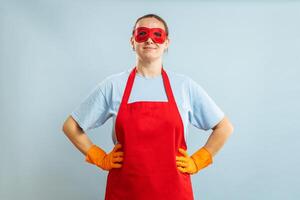 ung självsäker hemmafru i rengöring superhjälte kostym på blå bakgrund foto