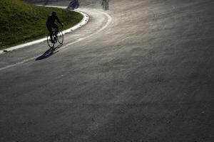 silhuett av en cyklist på de cykel-racing Spår i de parkera. foto