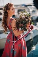 ung modell flicka i en skön klänning med en bukett av blommor på de strand i Frankrike. flicka med blommor i vår provence på de franska riviera foto