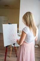 ung kvinna konstnär med palett och borsta börjar till måla abstrakt rosa bild på duk på Hem. konst och kreativitet begrepp foto