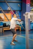 man spelar badminton i sport ha på sig på inomhus- domstol foto