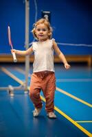 liten flicka tre år gammal spelar badminton i sport ha på sig på inomhus- domstol foto