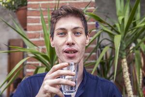 porträtt av en ung man medan dricka en glas av vatten foto