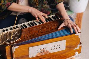 händer av en kvinna Sammanträde på de golv och spelar de harmonium under de öva av kundalini yoga foto