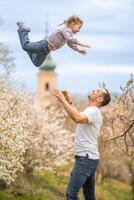 far och dotter har en roligt tillsammans under en blomning träd i vår parkera petrin i Prag, Europa foto