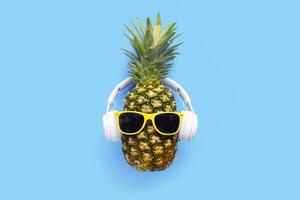 mogen ananas med solglasögon och hörlurar på blå bakgrund foto