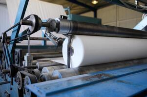 närbild av rulla lindning maskin. grekisk fabrik för de produktion av papper rullar för hygien. tillverkning av papper handdukar och toalett papper. selektiv mjuk fokus foto