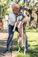 mogna man kissing hans räddade hund, en svart och vit spanska vinthund. foto