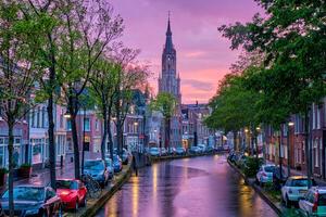 kanal med parkerad längs bilar i delft stad, nederländerna foto