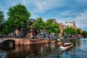amsterdam se kanal med båt, bro och gammal hus foto
