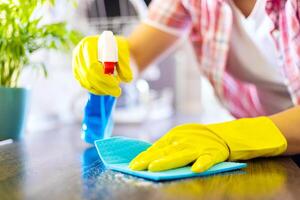 hemmafru i gul handskar våtservetter damm använder sig av spray rengöringsmedel och trasa foto