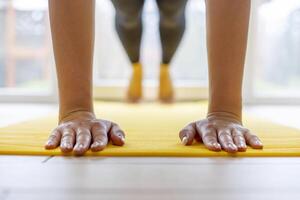 händer nedtryckt platt på gul yoga matta, träna session inomhus foto