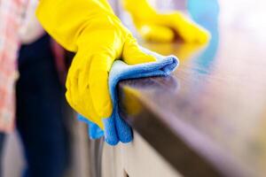 kvinna hand rengöring de disken i de kök med en blå mikrofiber trasa foto