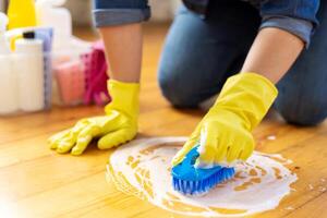 kvinna i sudd handskar är använder sig av golv borsta till rengöring golv foto