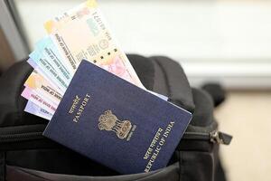 blå indisk pass med pengar och flygbolag biljetter på turistiska ryggsäck foto