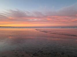 solnedgång på playa de famara, lanzarote, målarfärger de himmel med vibrerande nyanser, gjutning en fascinerande glöd över de horisont. hisnande syn den där fångar de väsen av lugn och naturlig skönhet. foto