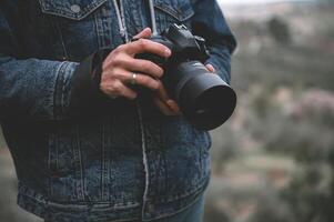 närbild professionell kamera i de händer av manlig resande fotograf foto