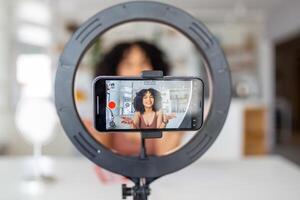 ung kvinna influencer använder sig av henne smart telefon för filmning en vlog posta. foto