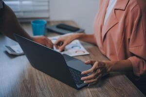 porträtt av asiatisk ung kvinna som arbetar på laptop på kontoret foto