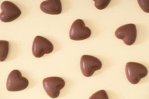 kreativ kärlek mönster sammansättning tillverkad med choklad hjärtan på ljus beige bakgrund. minimal kärlek begrepp. trendig choklad hjärtan aning. choklad estetisk. romantisk platt lägga. foto
