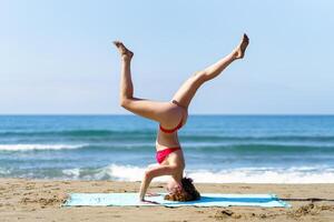 smal lady utför yoga på kustlinje foto