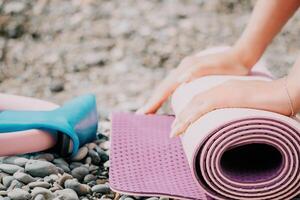 pilates magi ringa och sudd band på yoga matta nära hav. kvinna kondition yoga begrepp. friska livsstil harmoni och meditation. foto