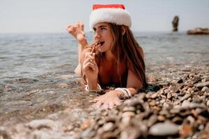 kvinna resa hav. Lycklig turist njut av tar bild på de strand för minnen. kvinna resande i santa hatt utseende på kamera på de hav bukt, delning resa äventyr resa foto