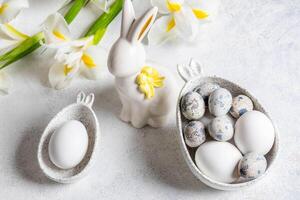 två tänkte skålar med kanin öron med ägg, keramisk kanin, vit iris blommor på vit. påsk. foto