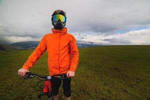 porträtt av en racer i full skydd av en full ansikte mask på en cykel eller motorcykel i de sommar berg. de begrepp av lockar ungdom till utomhus- sporter foto