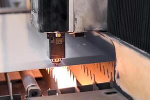 gammal automatiserad cnc laser maskin nedskärningar rostfri stål ark. laser skärande av metall foto