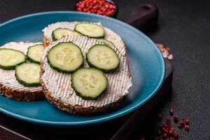 utsökt vegetarian smörgås med grillad rostat bröd, grädde ost, gurkor och frön foto