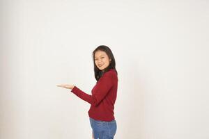 ung asiatisk kvinna i röd t-shirt som visar och innehav på öppen handflatan kopia Plats isolerat på vit bakgrund foto