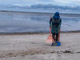 någon vem är bärande ut skräp rengöring aktiviteter runt om de strand, grön jorden, kust städa dag foto