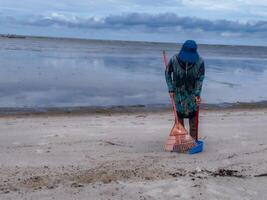 någon vem är bärande ut skräp rengöring aktiviteter runt om de strand, grön jorden, kust städa dag foto