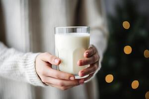 ai genererad torr januari begrepp. närbild av kvinna händer innehav en glas av mjölk mot bakgrund av en jul träd inomhus foto