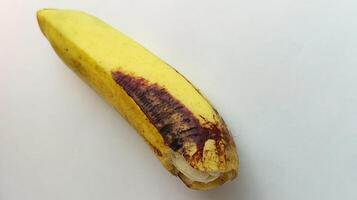 gul banan med brunaktig svart fläckar på en vit bakgrund foto