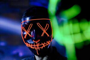 man bär neon mask i en vagt belyst rum. foto