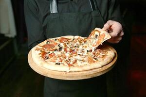 person innehav pizza på trä- tallrik foto