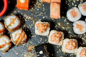 sushi rullar och ätpinnar på skiffer styrelse foto