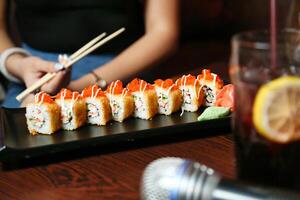 färsk sushi och ätpinnar på trä- tabell foto